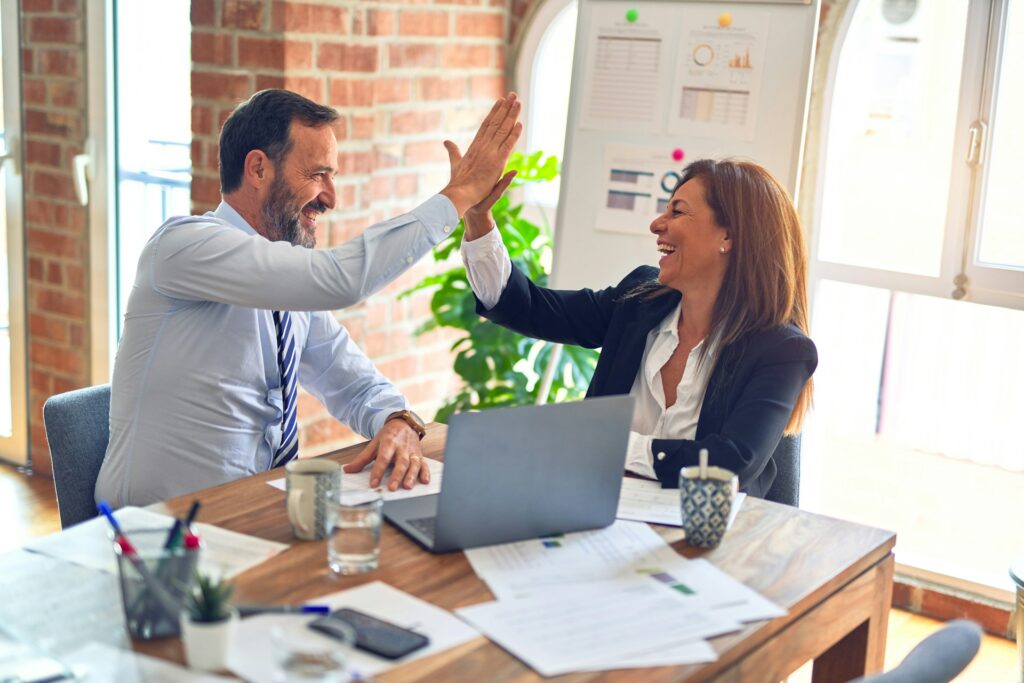 Eine Frau und ein Mann im Businessumfeld, die zu einem High Five einschlagen